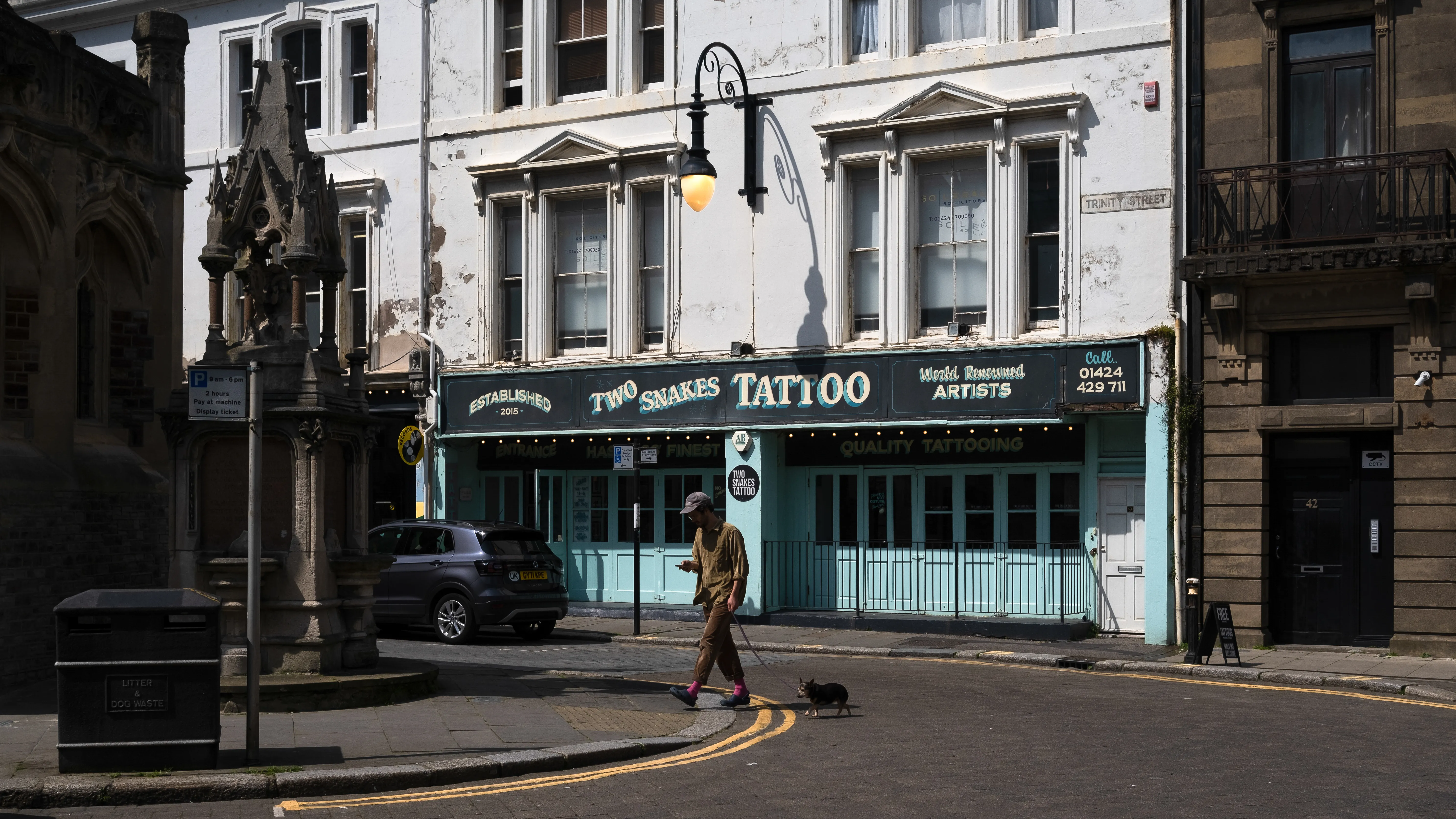 Street corner in Hastings with a tattoo shop and a passer-by in the morning light