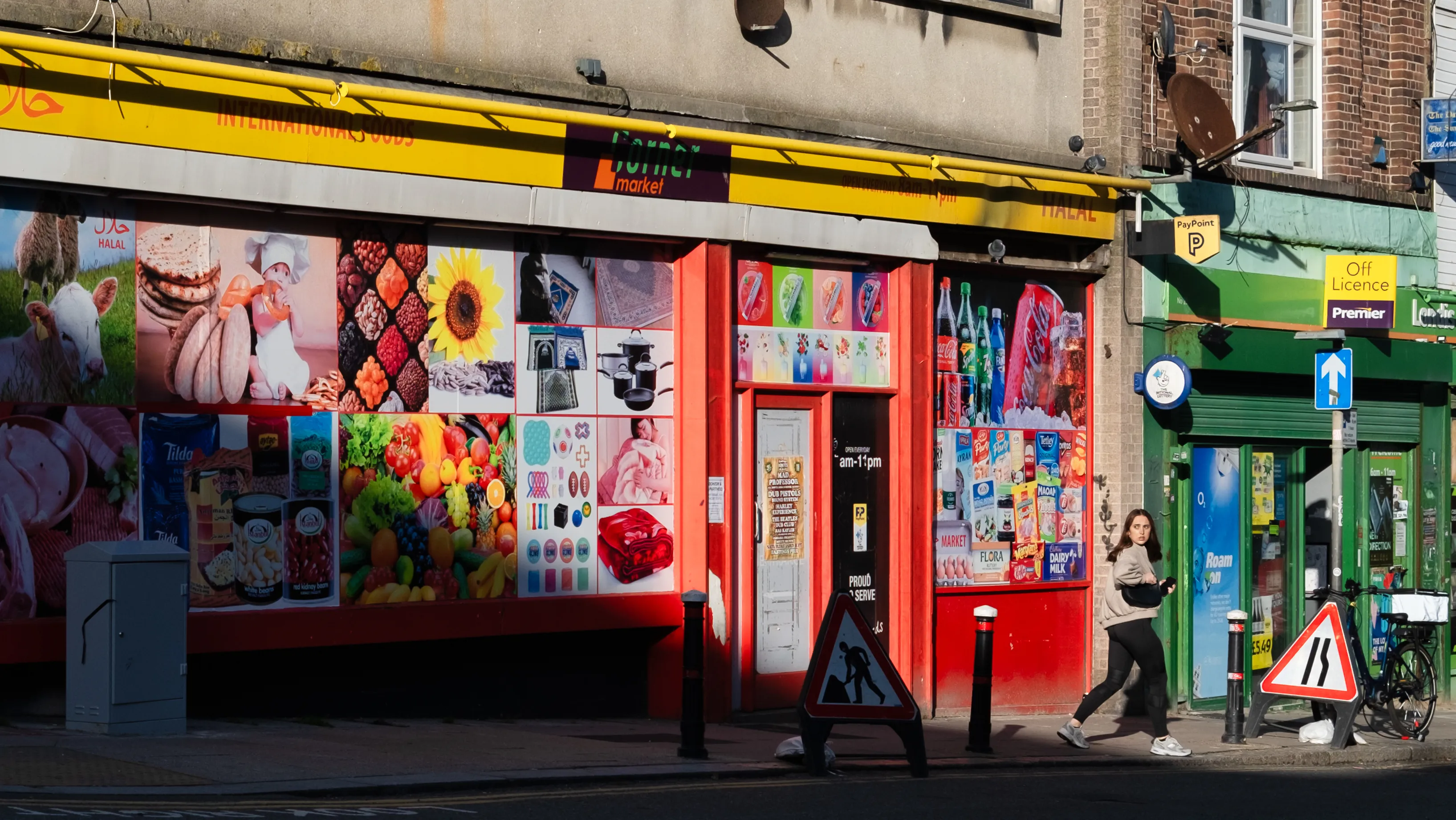 Colourful shopfronts in Hastings, a runner passes a bright red facade