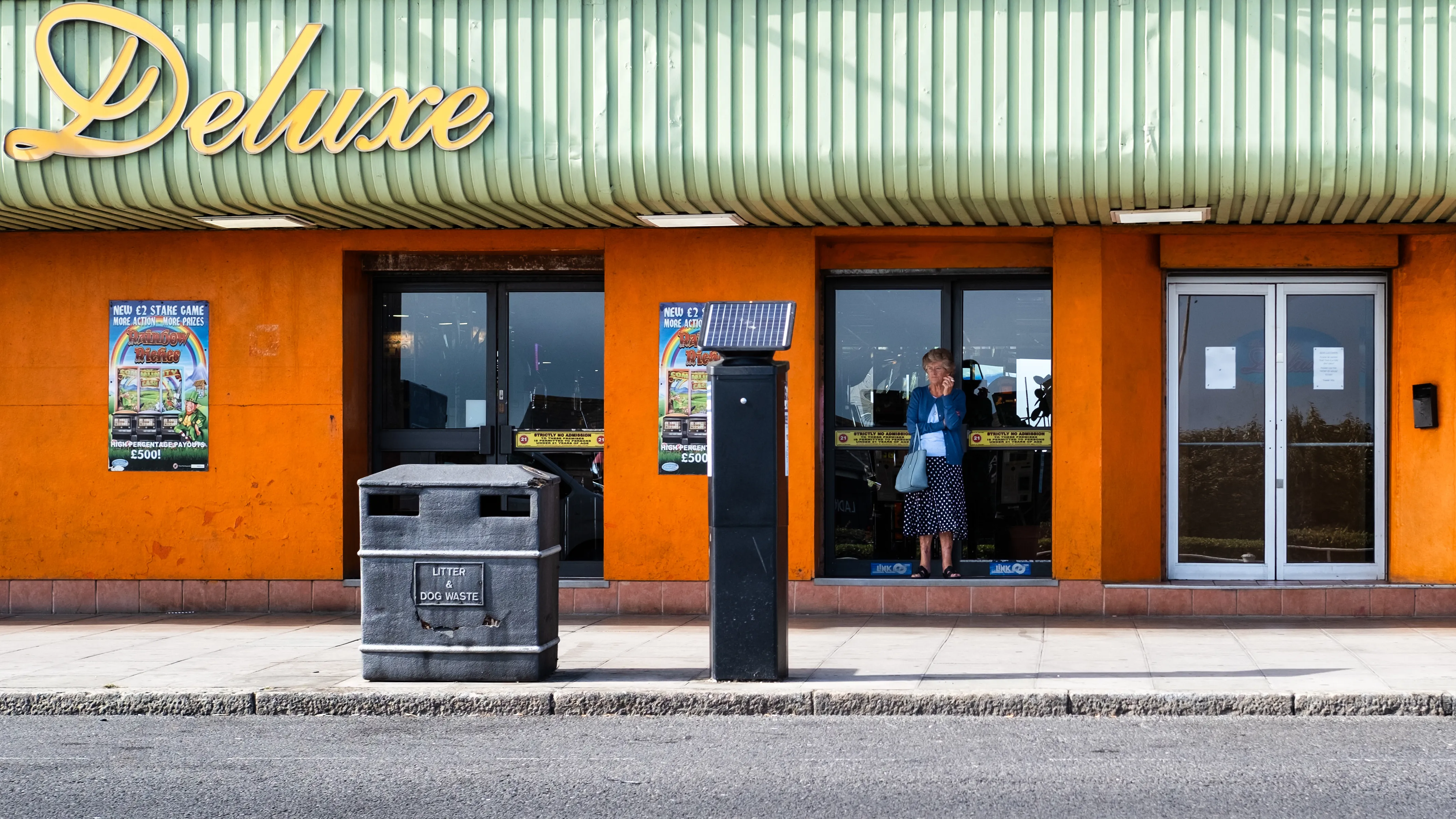 Orange facade of the Deluxe amusement arcade with a bus stop in front of it