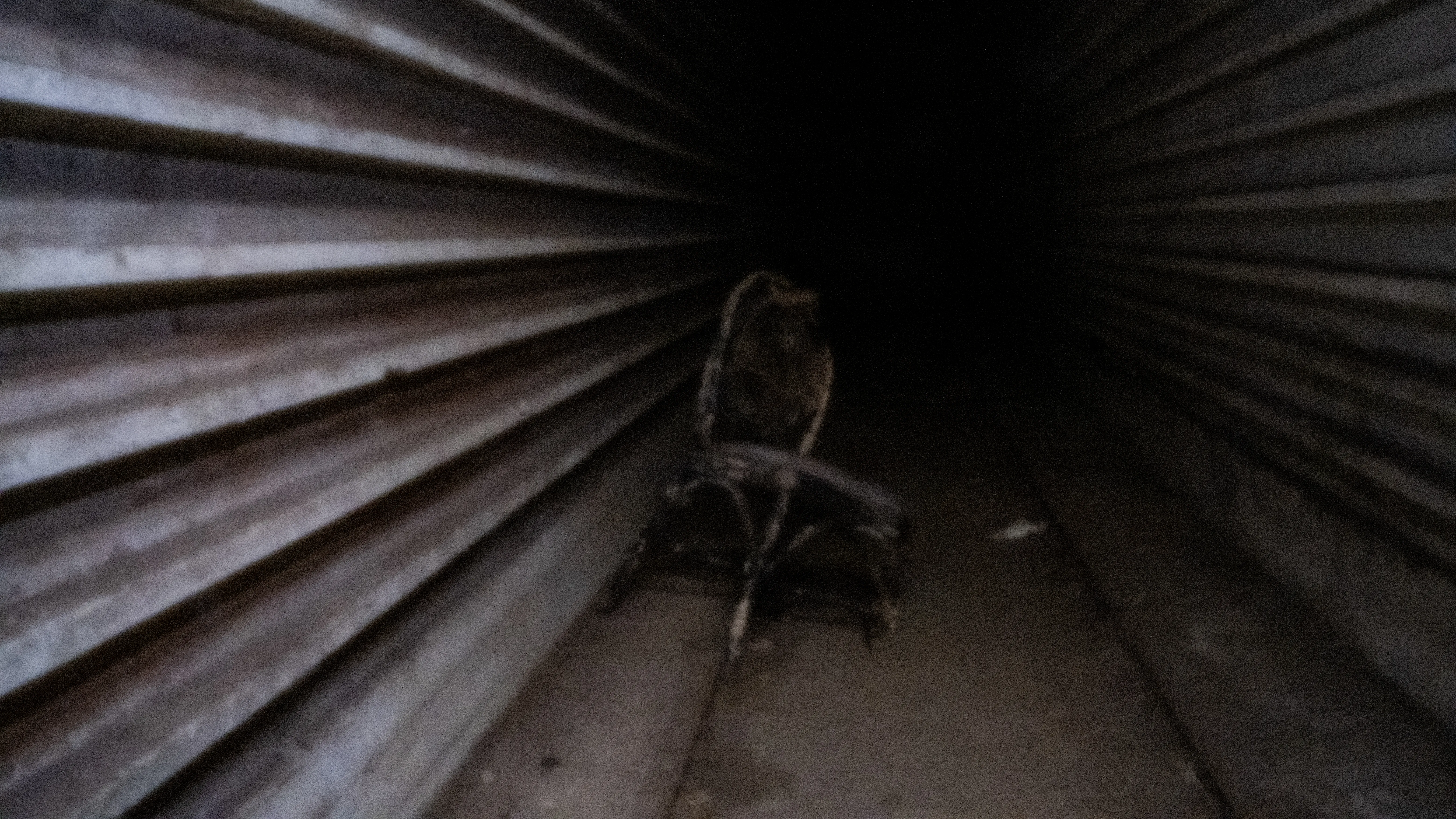 Abandoned chair in a dark corridor of corrugated iron