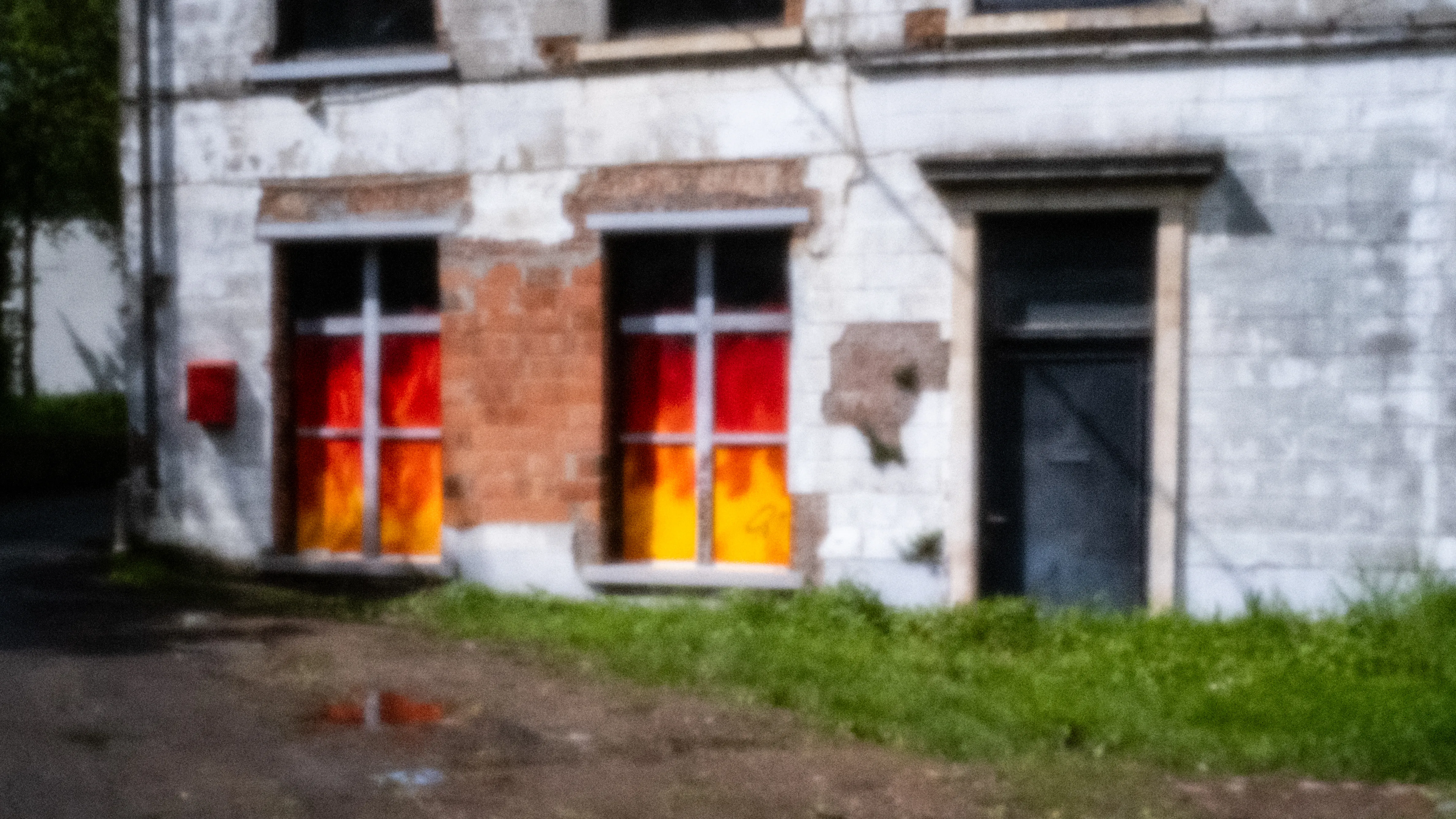 Derelict house with doors painted over in orange and red