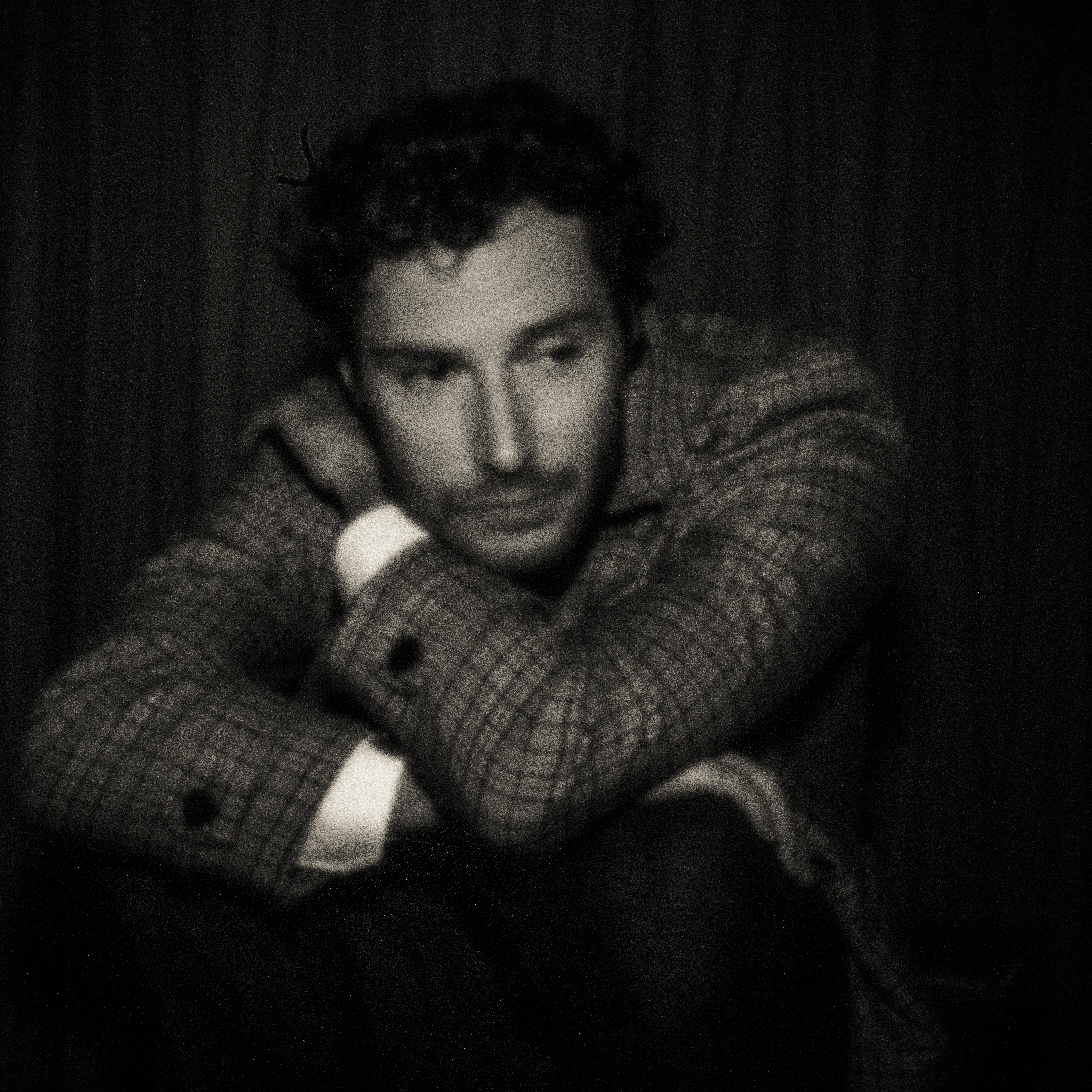 Pinhole-portret van een zittende man in geruit jasje, armen over elkaar