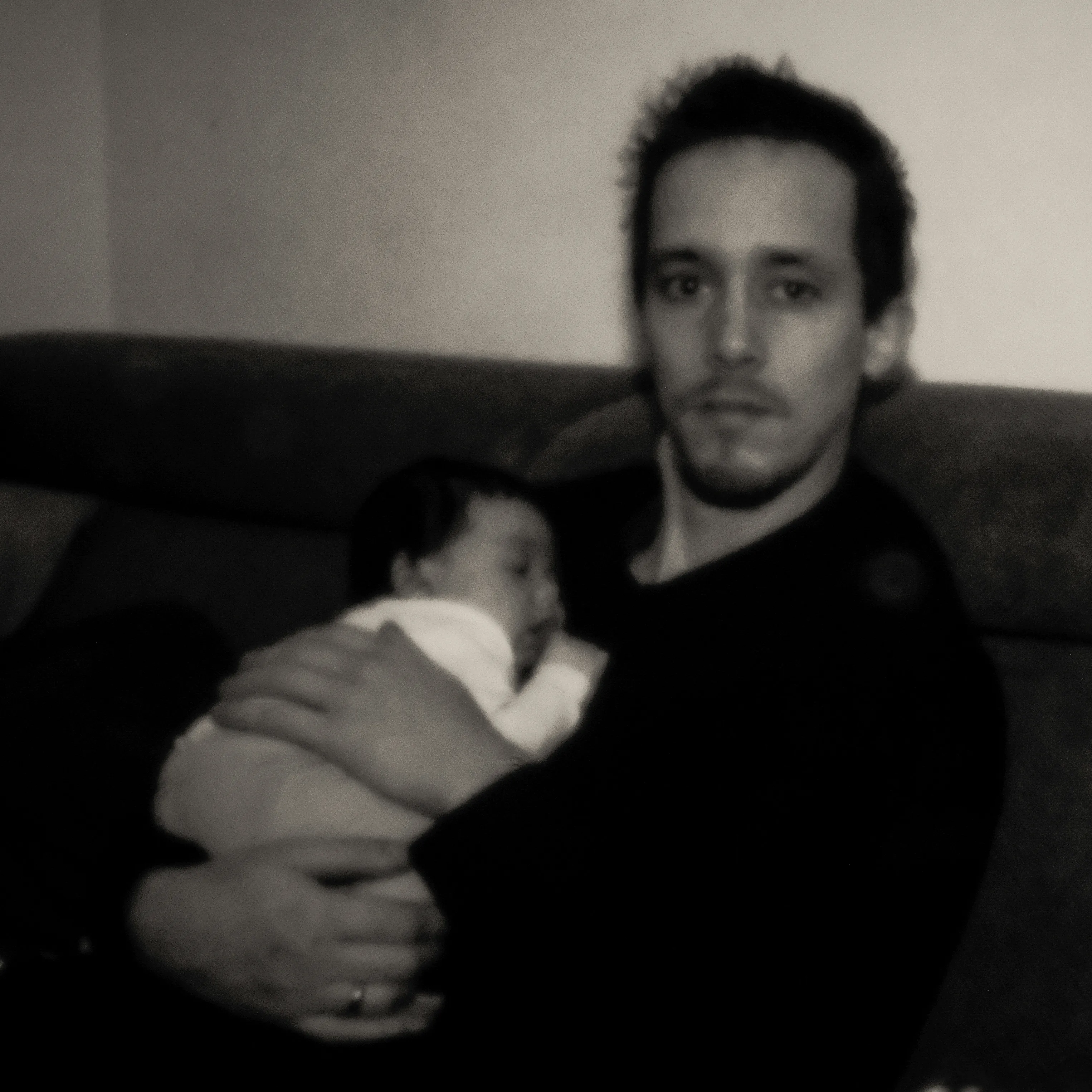 Pinhole portrait of a father holding a baby in his arms