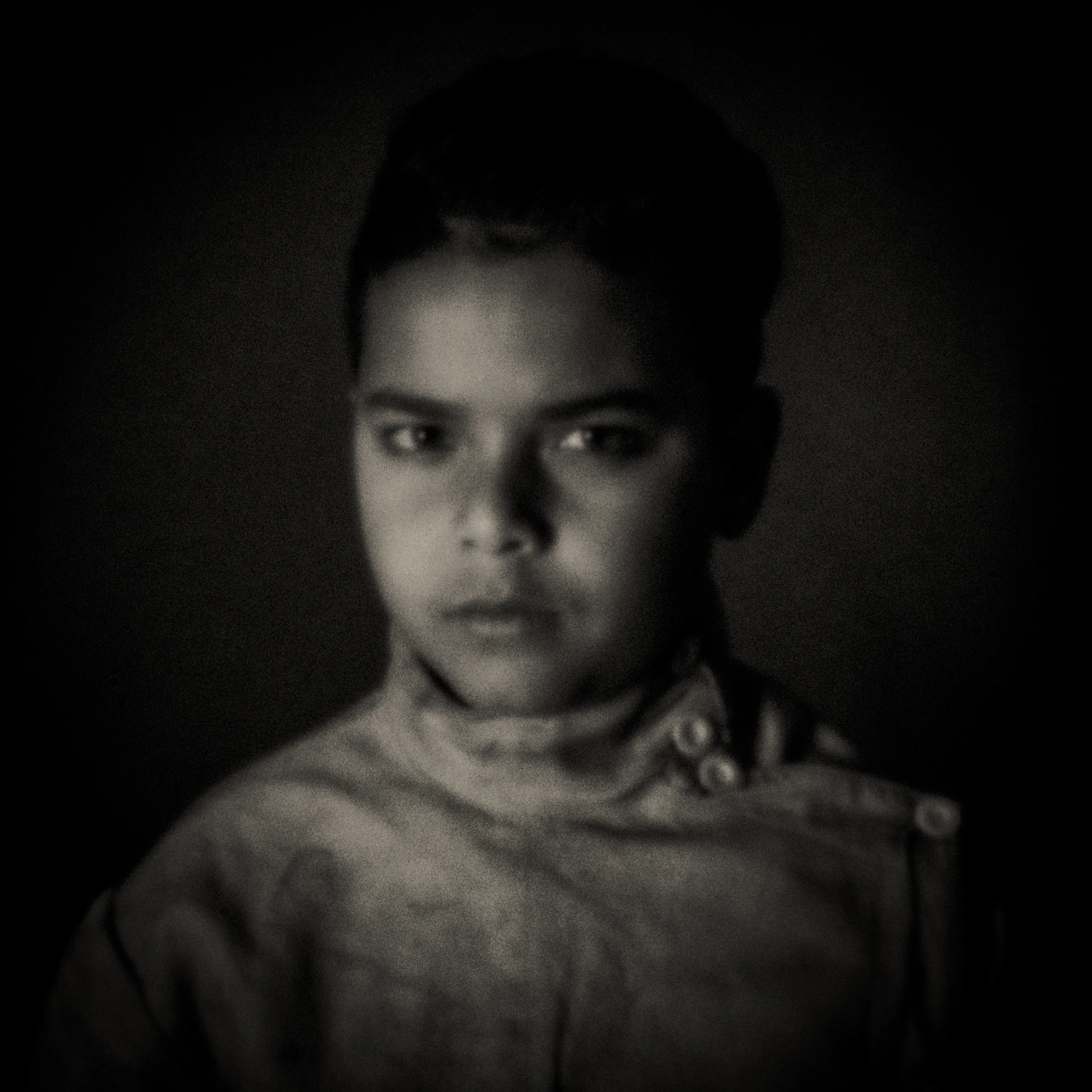 Pinhole-portret van een jongen in donkere trui, zacht licht