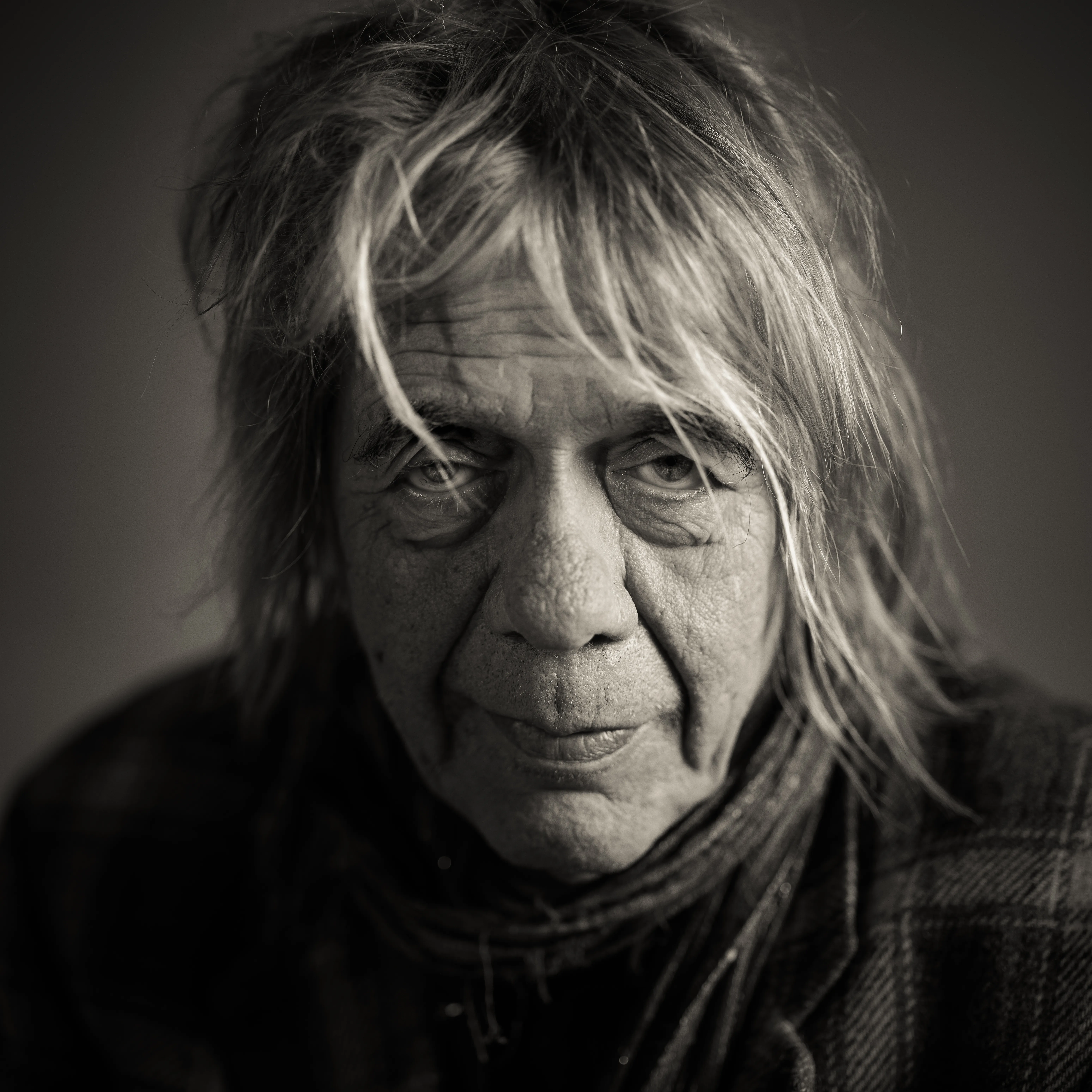 Portret van een oudere persoon met lang grijs haar, zacht licht op het gezicht