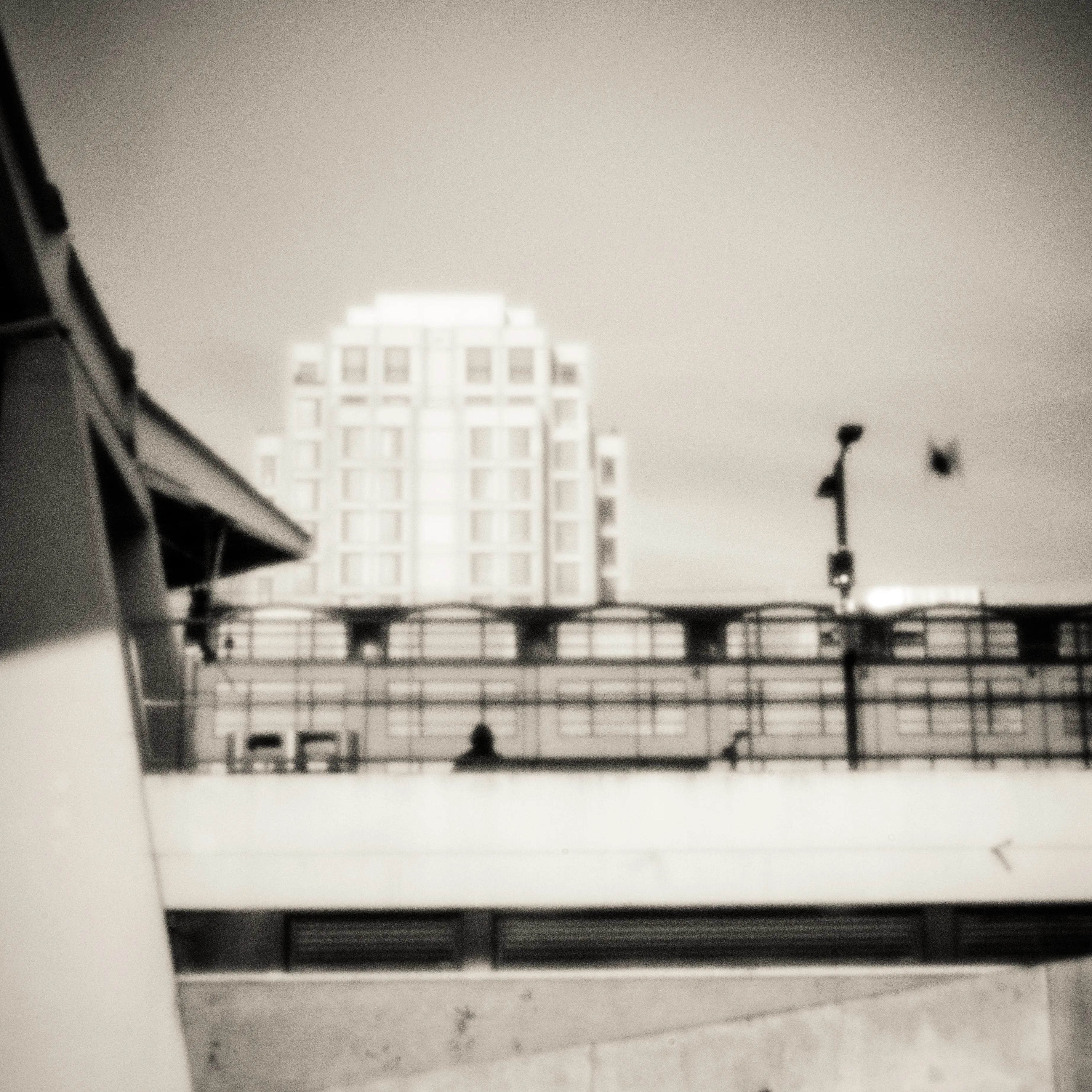 White building above a viaduct, photographed with a pinhole camera