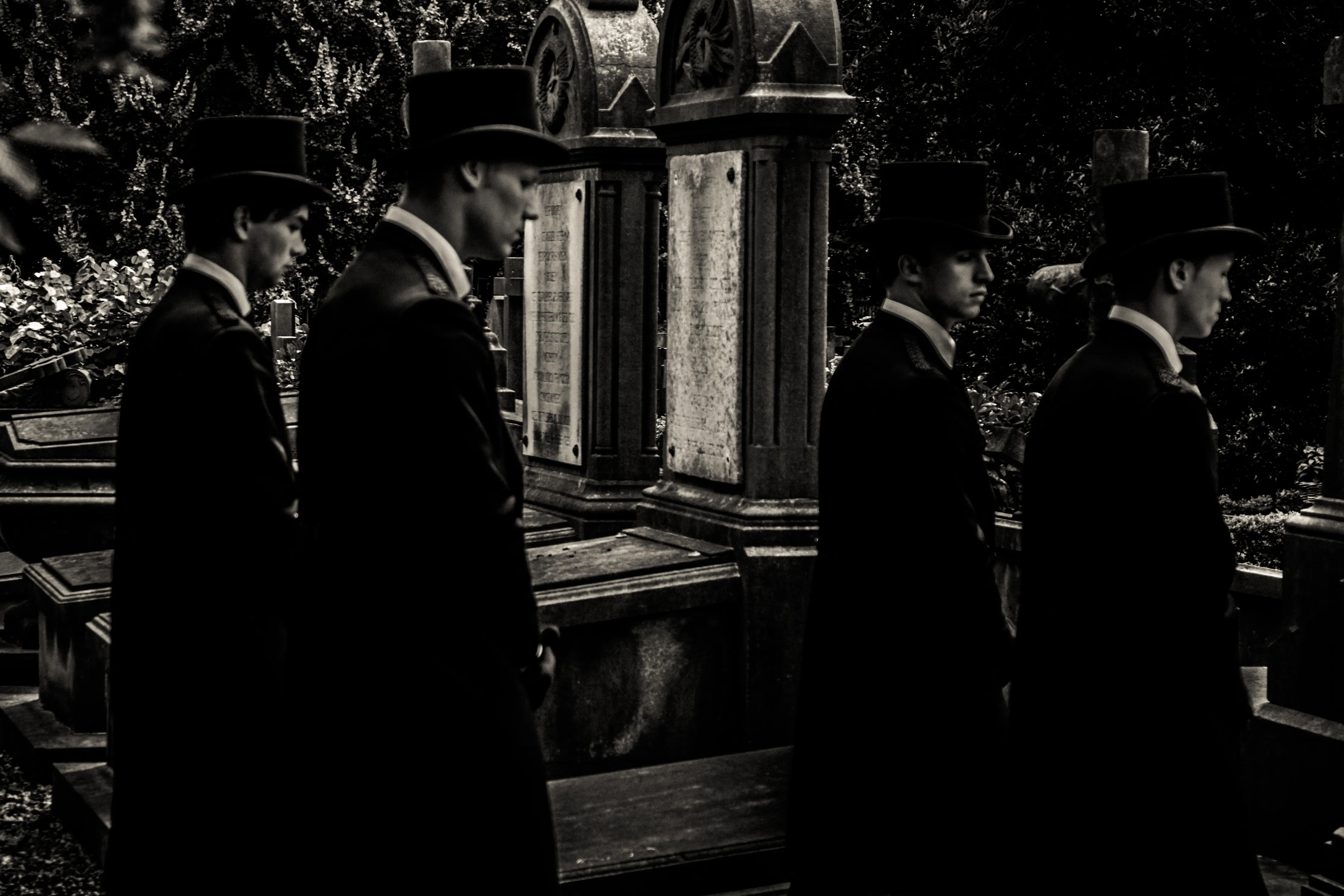 Black and white image of men in top hats at a funeral procession