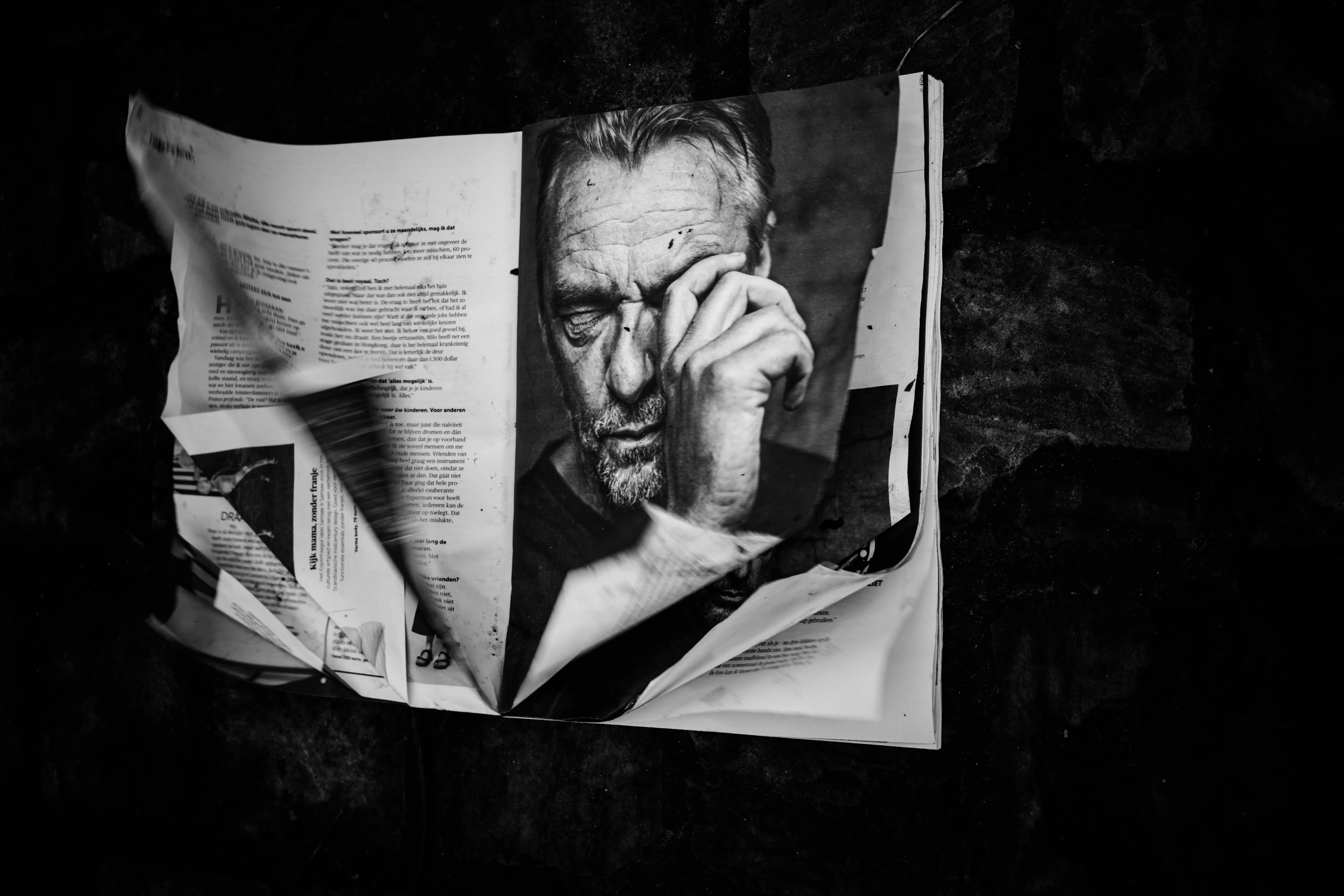 Man reading an open magazine that covers half his face