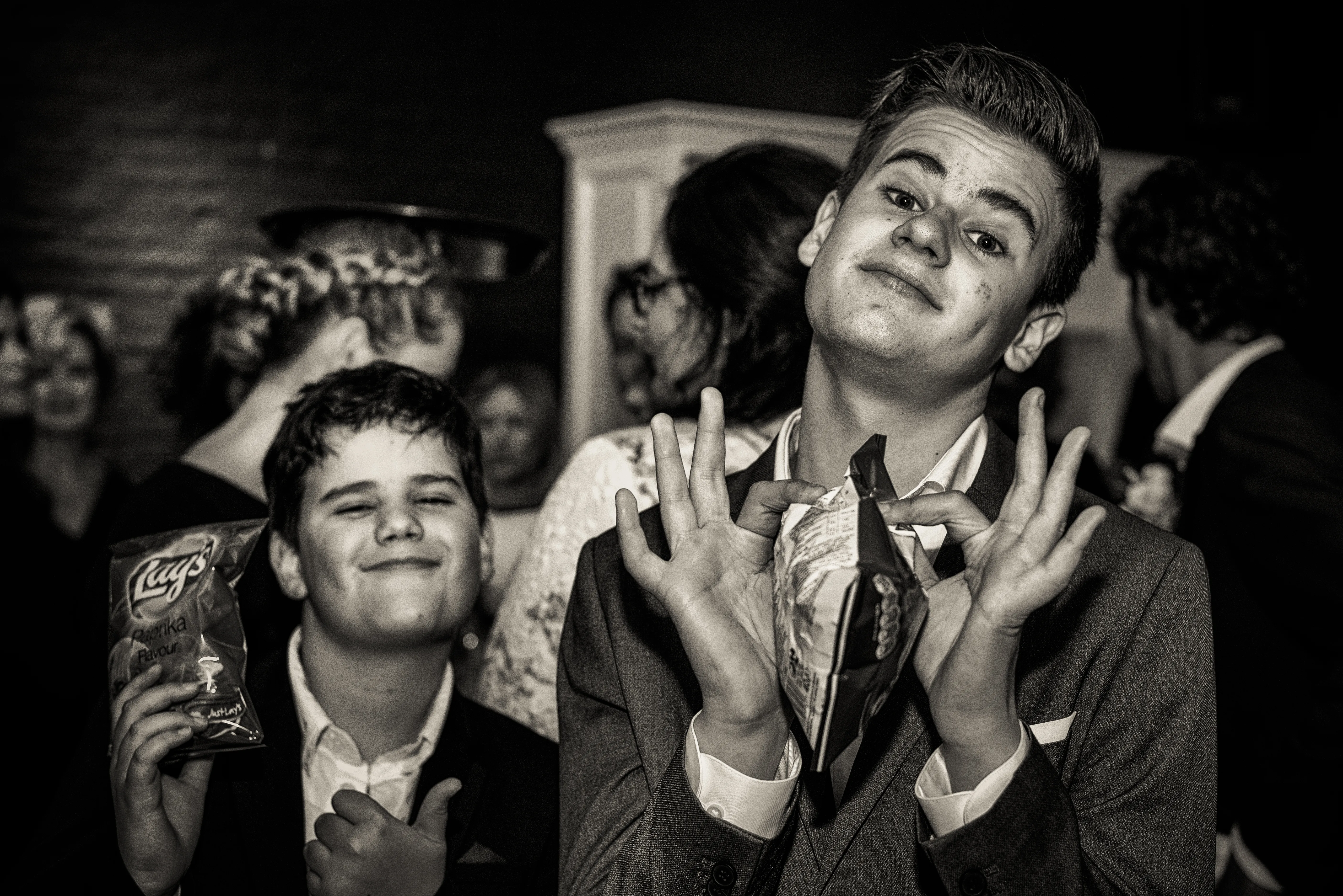 Two boys posing exuberantly at a party, black and white