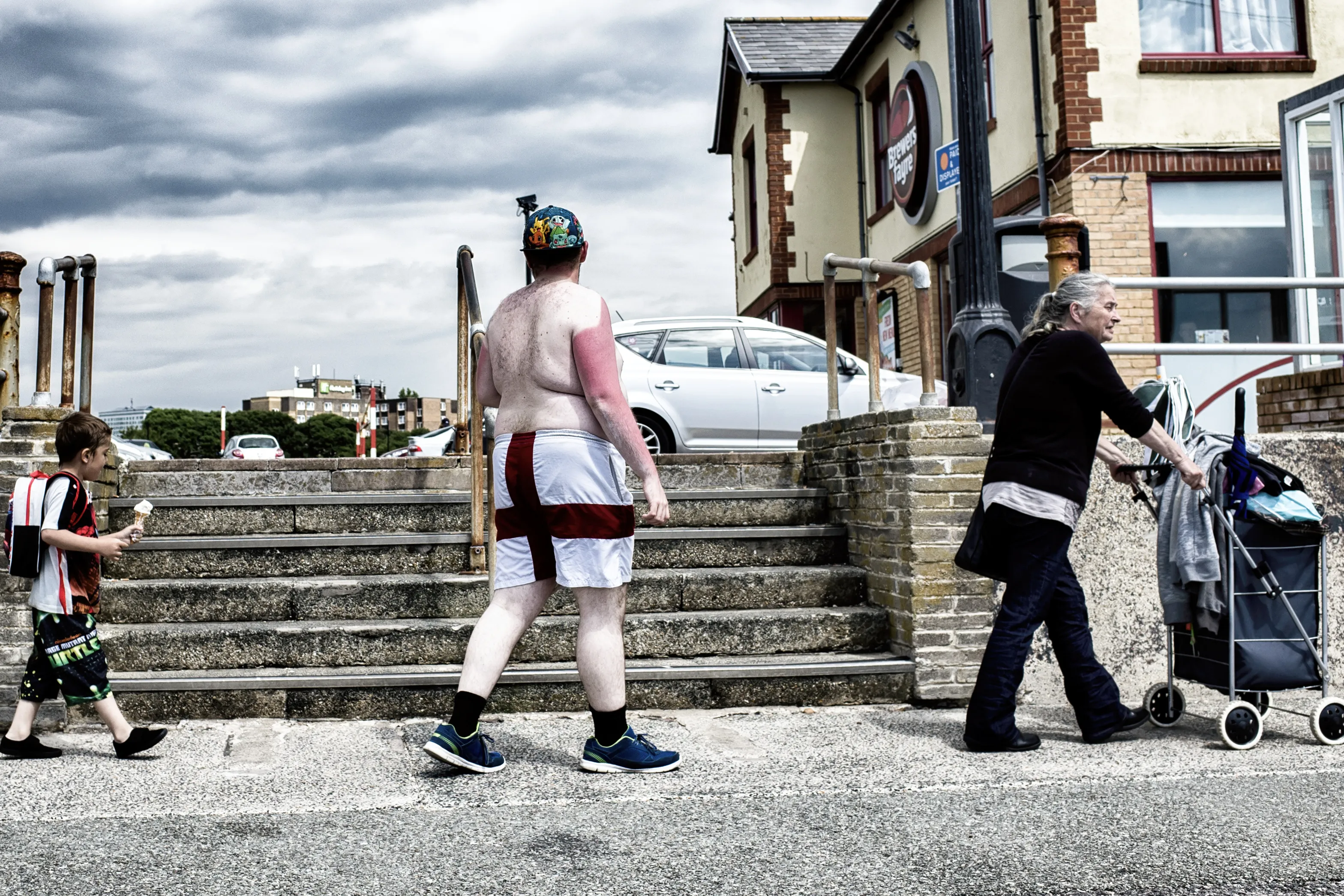 Street scene with a man in a dress on a staircase and a woman with a pram