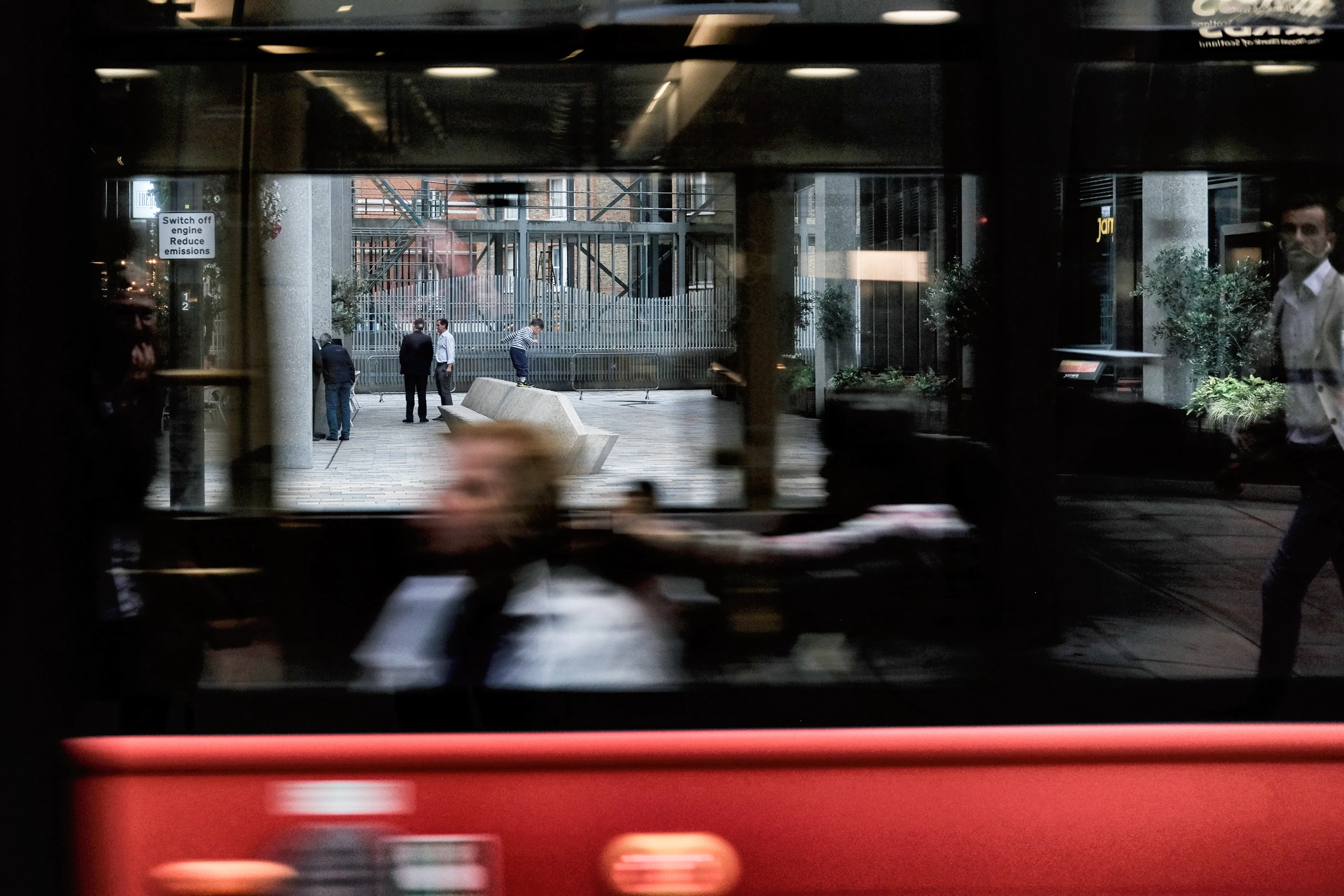 Blurred figure behind the window of a red bench, movement in colour